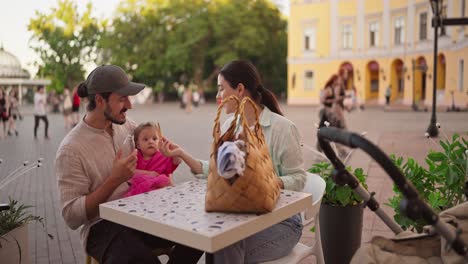 a family enjoys a meal at a cafe table outdoors.