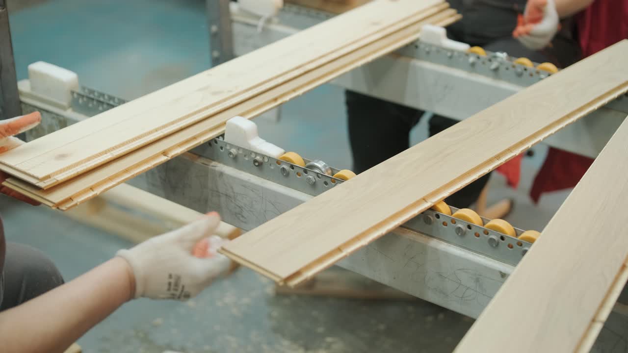 Operai che movimentano e impilano assi da pavimento in legno in una fabbrica