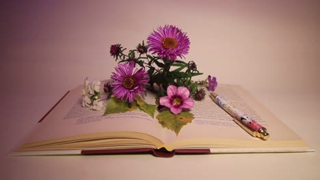 close up of flowers and pen on the book in the dark