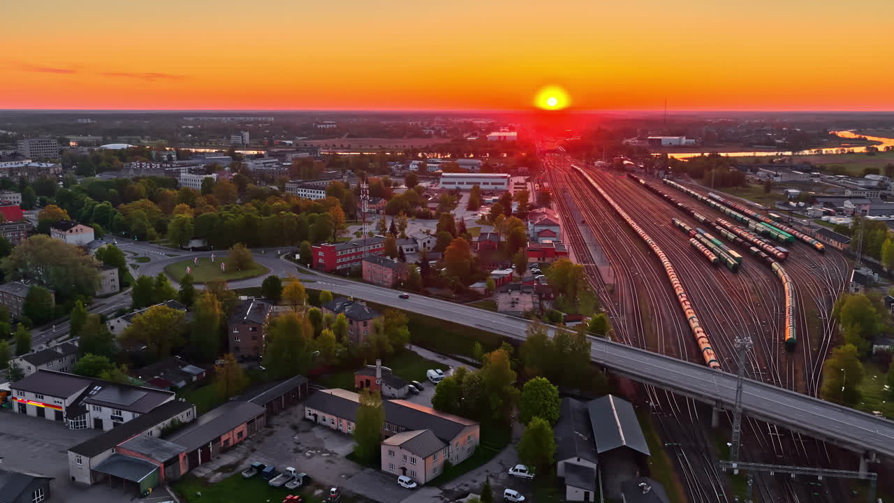 City sunset with railway yard, aerial view of tracks and buildings at golden hour