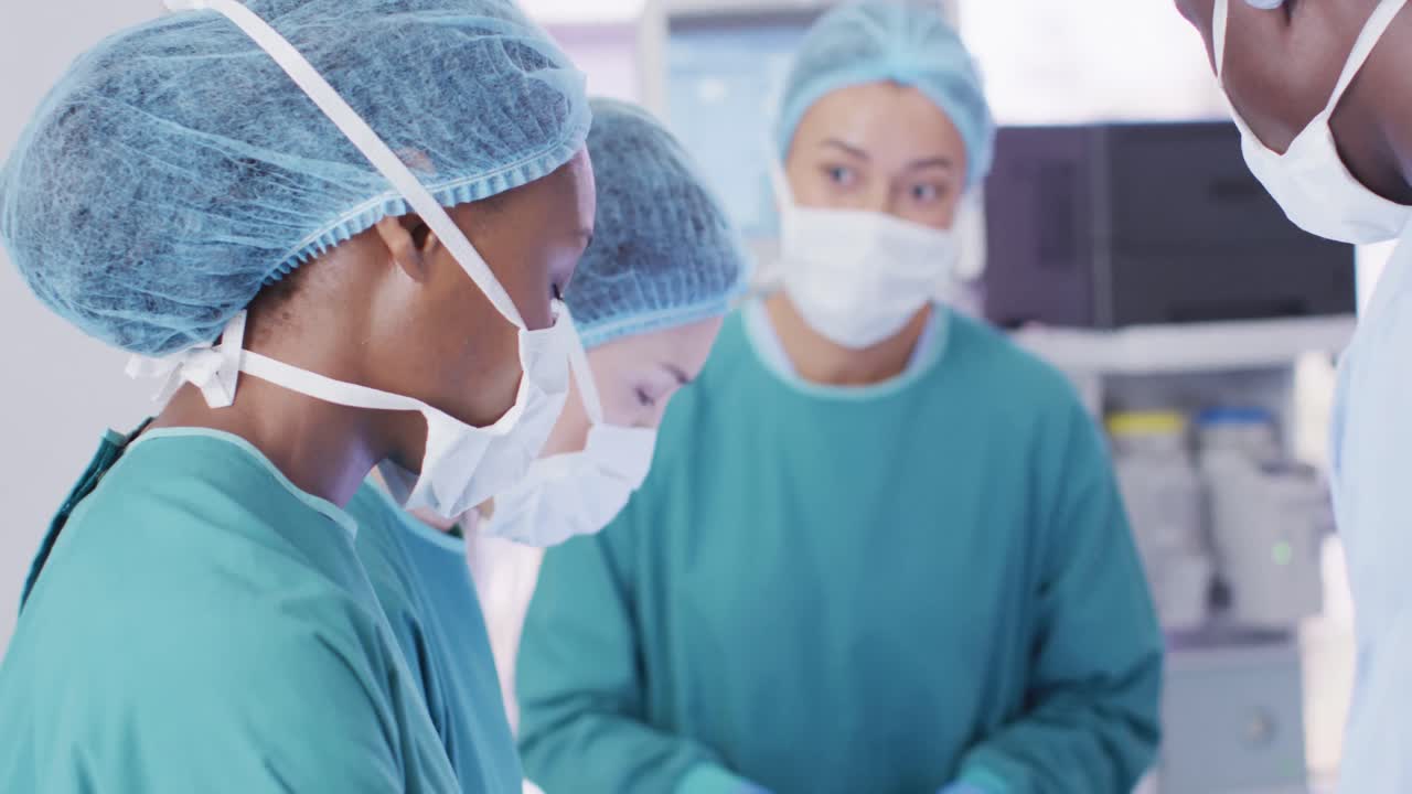 Video di una chirurga afroamericana che guarda in camera durante un'operazione con colleghi eterogenei