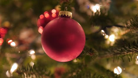 matte-red-ball-ornament-on-Christmas-tree-with-bokeh-lights-4k