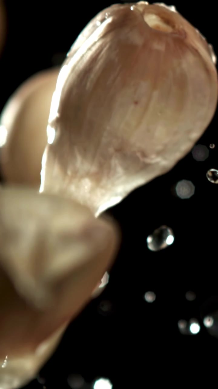 Spicchi d'aglio freschi che schizzano nell'acqua al rallentatore