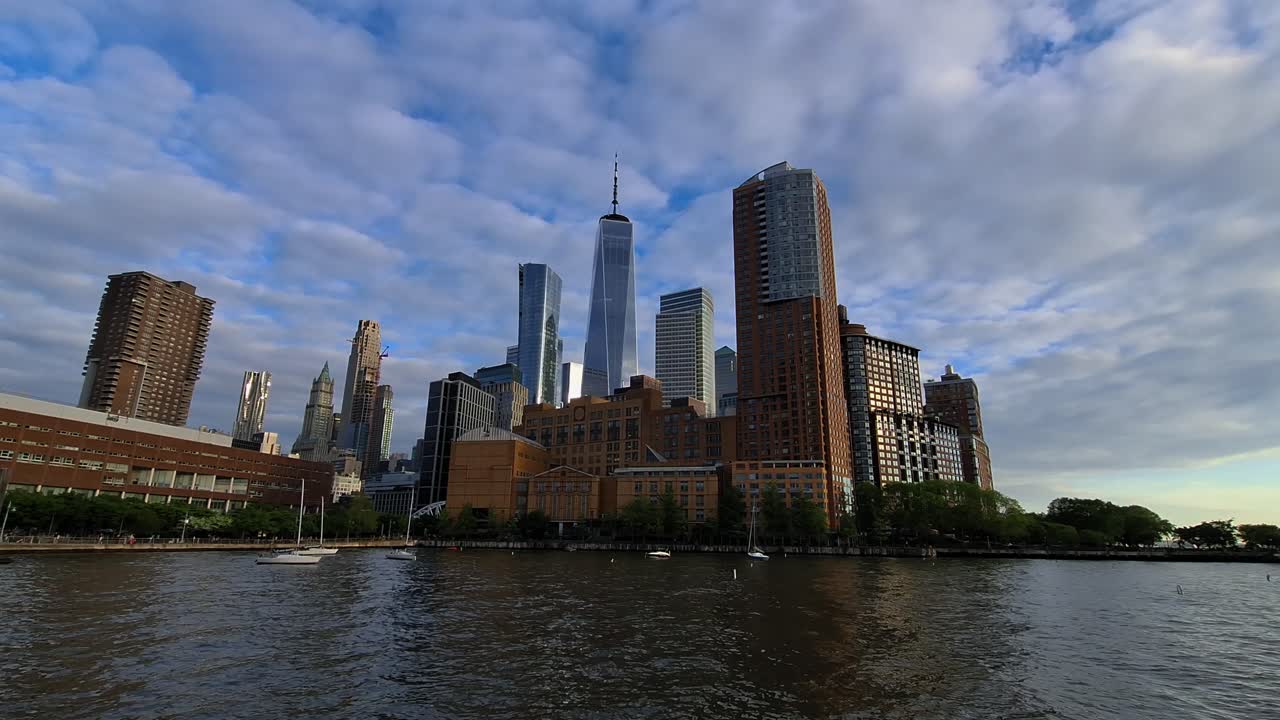 Modern skyscrapers and residential buildings rise along the waterfront with reflections on the river in New York, United States