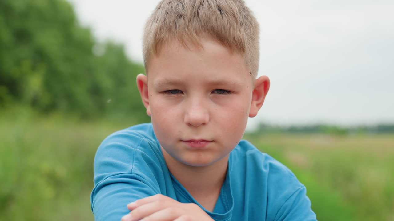 들판에서 결연한 표정으로 자전거에 팔짱을 끼고 카메라를 응시하는 백인 소년, 초록색 초원과 흙길 배경, 은은한 회복력과 커져가는 결의, 자연광, 희망찬 분위기