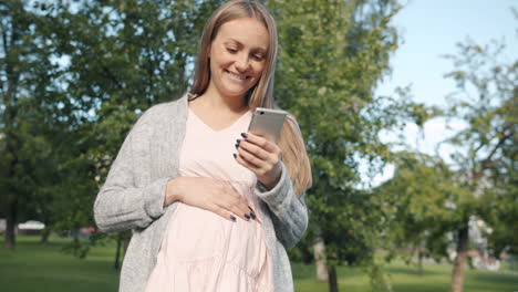 pregnant woman using a mobile phone in a park