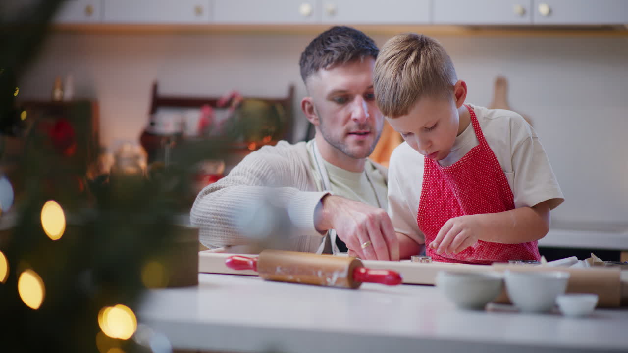 Junge hilft Papa beim Backen von Weihnachtsplätzchen