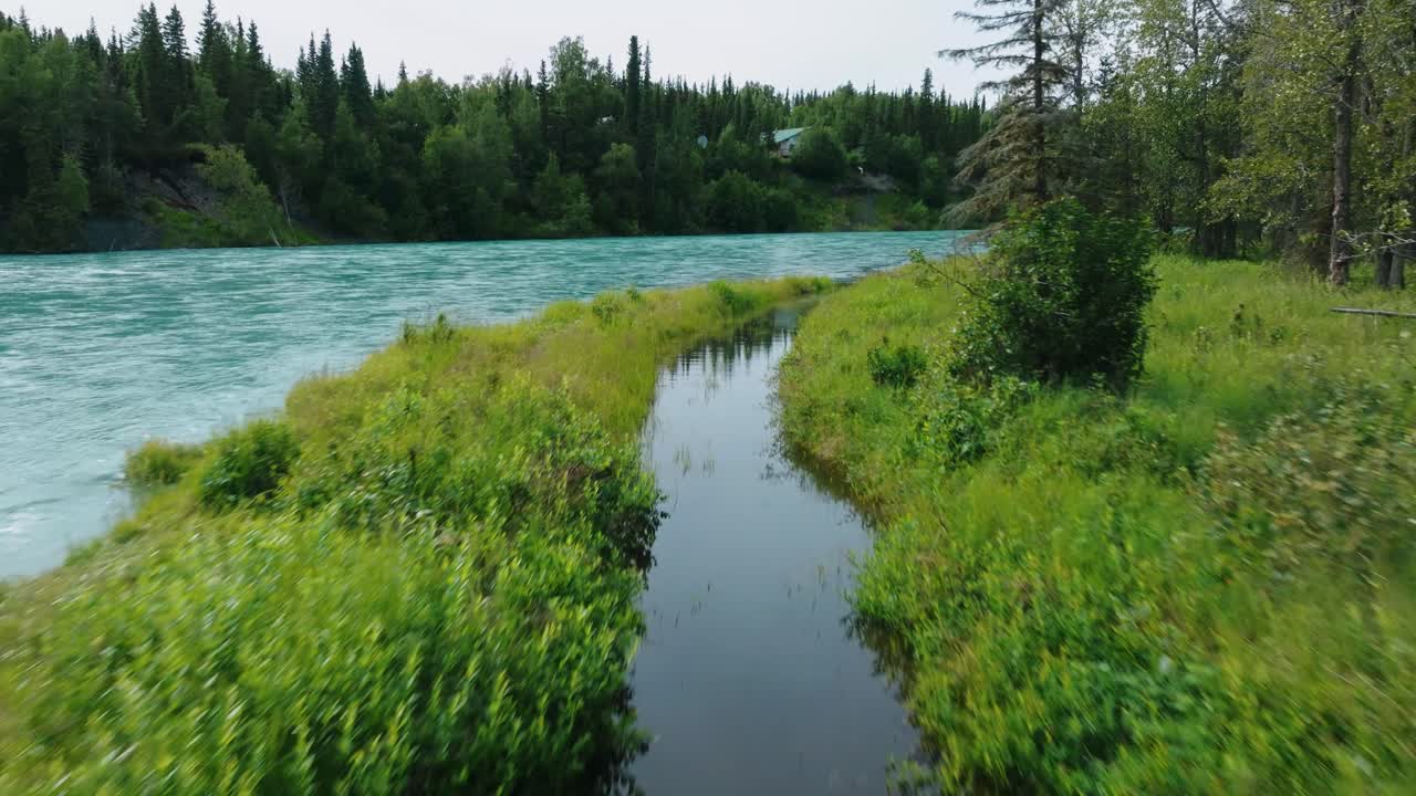 Aerial drone fly over Alaskan river inlet on the shoreline of pristine turquoise salmon fishing river