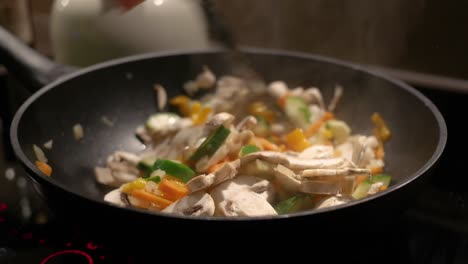 female hand stirs vegetables fried in a pan