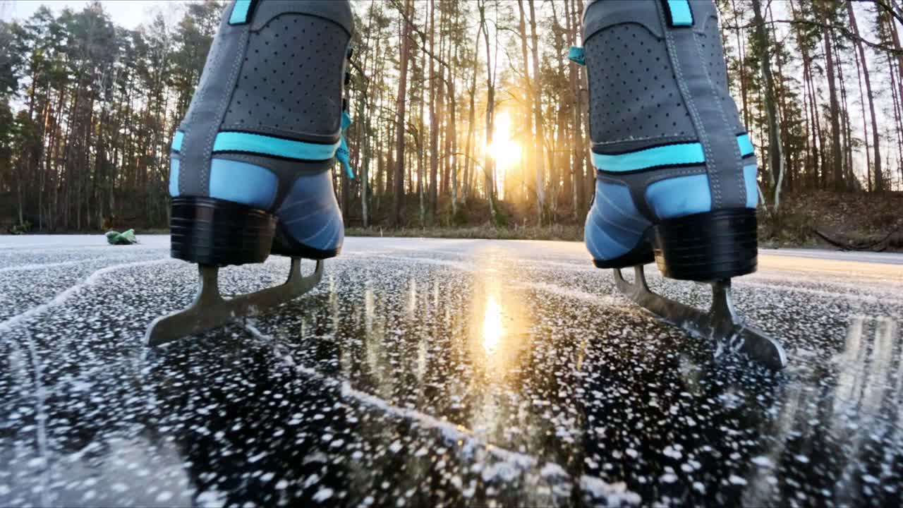 Low angle view of woman ice skating on frozen lake with sunset light