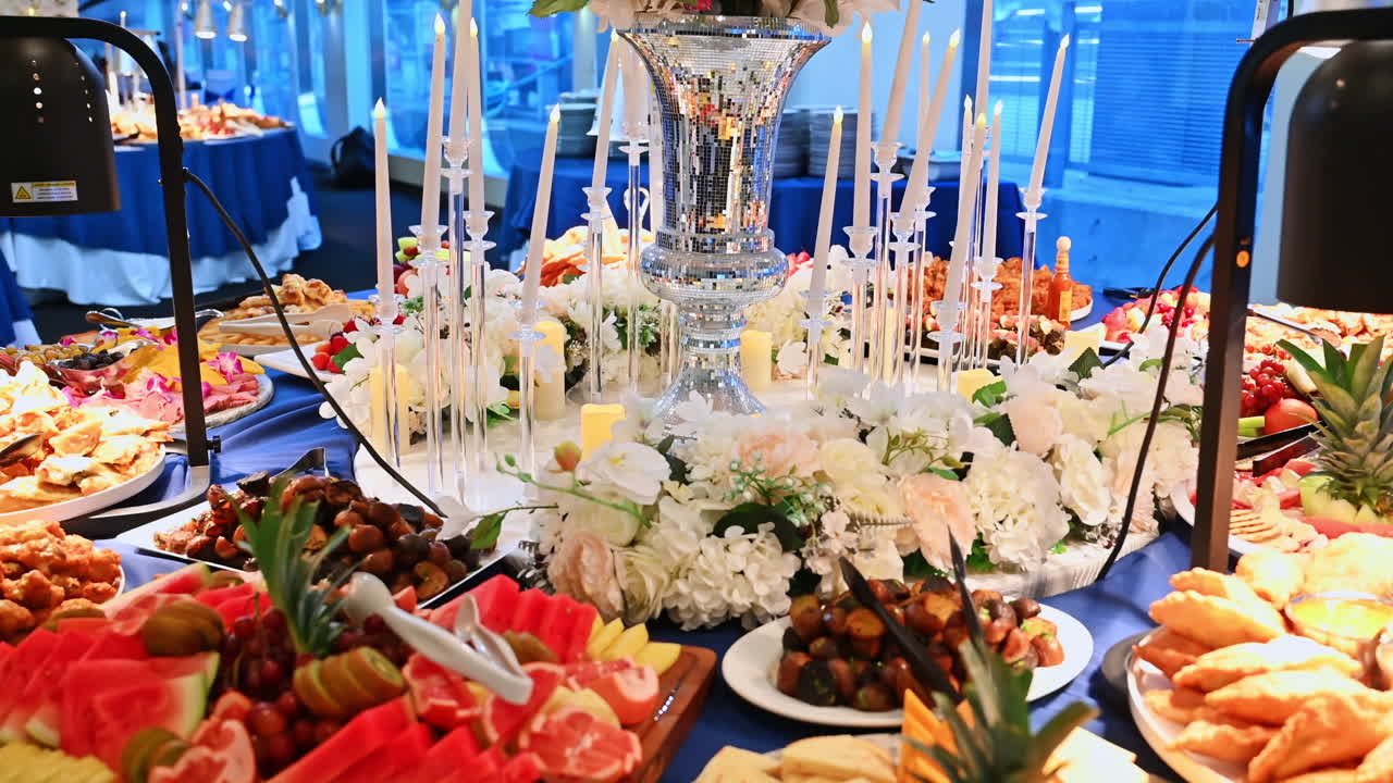 Buffet di lusso su nave da crociera con fiori e lume di candela. Tavolo da buffet decorato su una nave con centrotavola floreale, candele e piatti gourmet