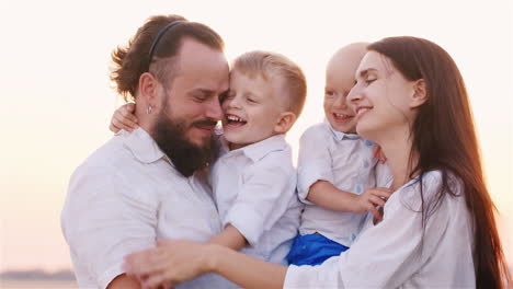 portrait of a young family with two young sons smiling at the camera hugging each other