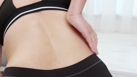 허리 통증으로 고통 받고 아픈 근육을 마사지하고 손으로 자기 마사지를하는 여성