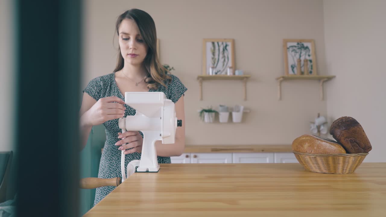 소녀 는 나무 테이블 위 에 있는 가정용 시리얼 밀더 를 손잡고 있다