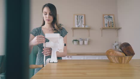 girl-puts-handle-to-home-cereal-grinder-on-wooden-table