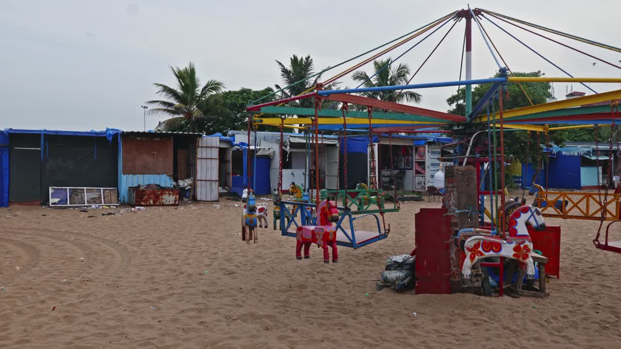 Round Carousel horses amusement rides with small business shops at marina beach, chennai, tamil nadu, india. evening time, stable shot, 4k.