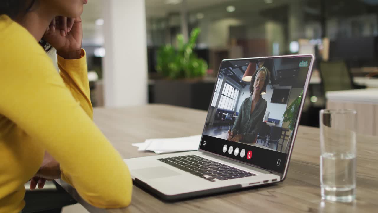 Biracial woman using laptop for video call, with business colleague on screen
