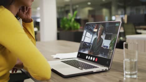 Mujer-Birracial-Usando-Una-Computadora-Portátil-Para-Videollamada,-Con-Un-Colega-De-Negocios-En-La-Pantalla