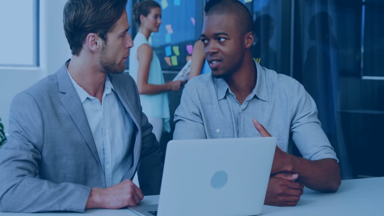 Discussing work, two men in office with colleagues at background, animation present