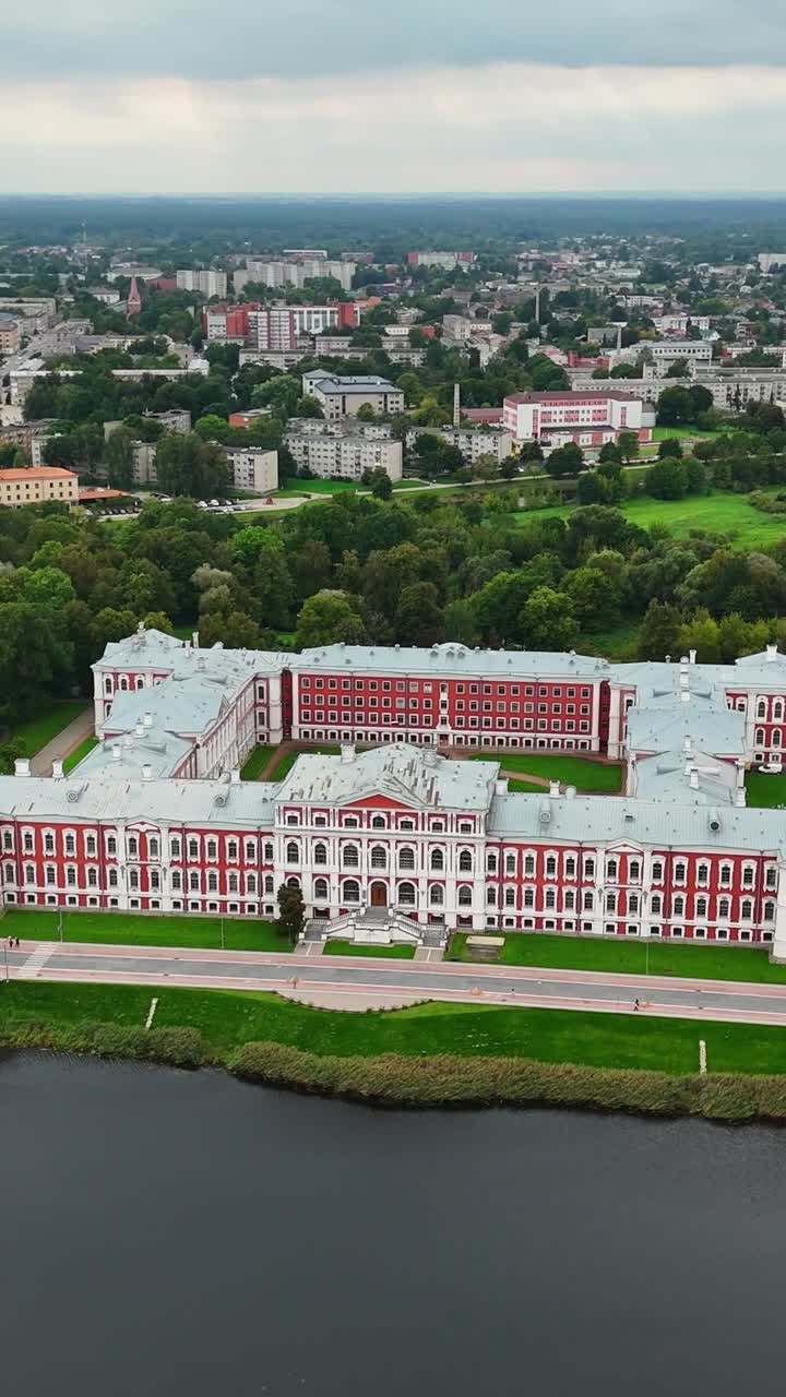 Vertical drone shot of Jelgava Palace by the river with city in background