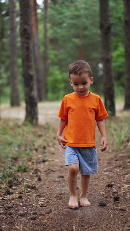 kid runs barefoot by the forest path with lots of pine cones on. healthy growing up in connection with nature. vertical video.
