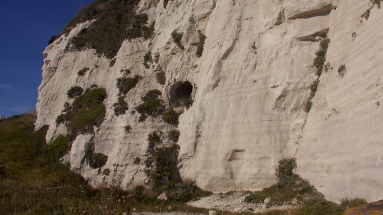 Inquadratura panoramica estremamente ampia delle scogliere bianche di Dover con un ingresso di tunnel rivestito in mattoni nel fianco delle scogliere.