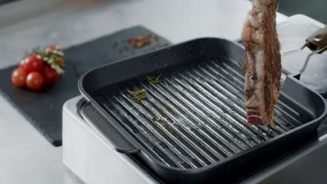 chef preparing meat at griddle. closeup chef hands turning steak with tongs.