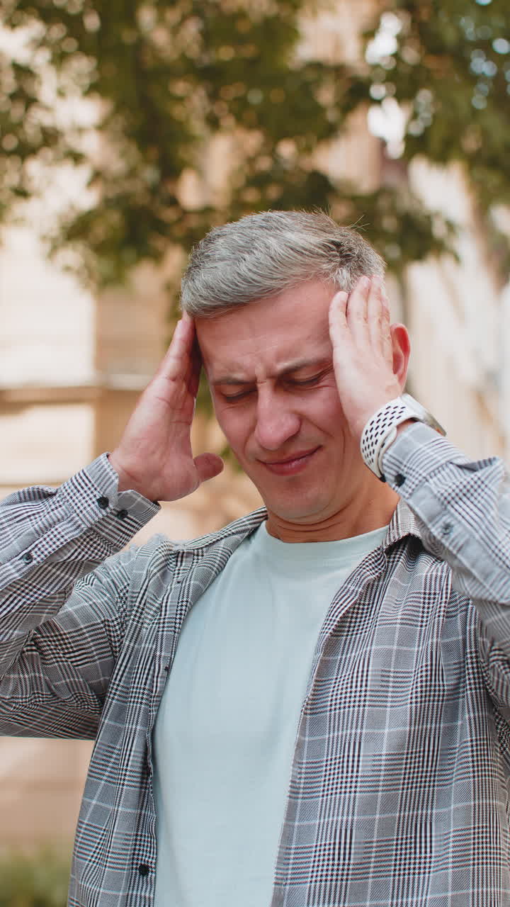 hombre descontento frotando las sienes para curar el problema del dolor de cabeza sufriendo de estrés por migraña en la calle