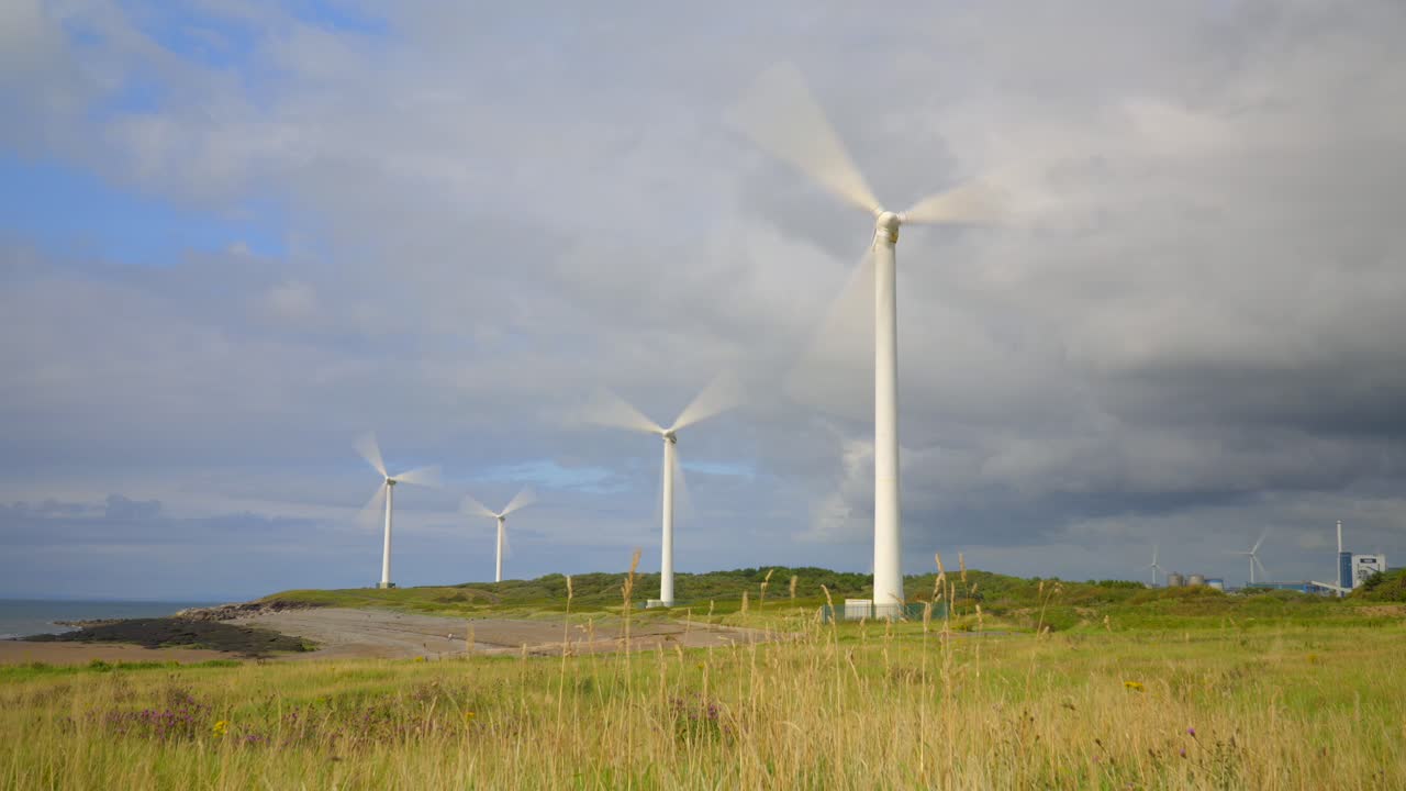 풍력 발전소가 회전하고 폭풍우 구름이 모여 빛으로 빛나는 수영장이 풍경을 가로질러 움직입니다.