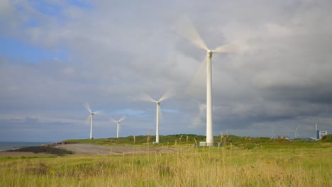 wind farm spinning and storm clouds gathering with sunlit pools moving across landscape