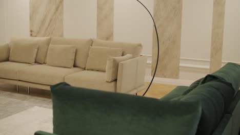 a cozy living room corner with a beige sofa, green velvet armchair, and an elegant floor lamp