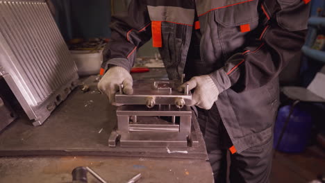 industrial worker with gloves assembling metal parts on machinery in a manufacturing workshop