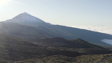 majestic teide mountain reveal with sun flare and white cloud bank.  aerial rising left.