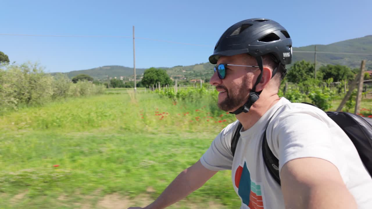 Man riding a bike through vineyards and olive orchards in Tuscany, Italy