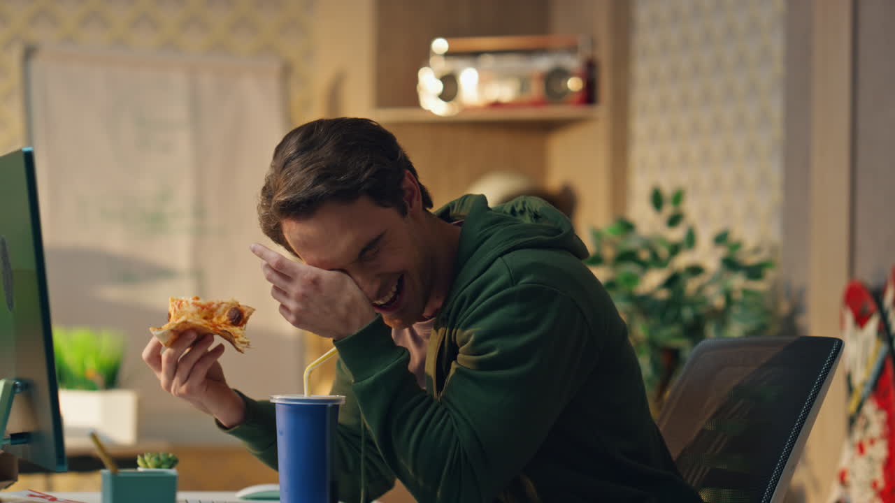 смеющиеся мужчины на обеденном перерыве в офисе. дизайнеры наслаждаются пиццей, веселясь.