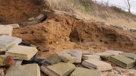 broken tiles scattered across beach from damaged sea wall