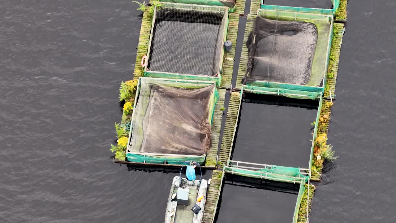 Overhead drone footage captures floating fish cages and a small boat on a calm reservoir, with steady lighting and minimal camera movement throughout