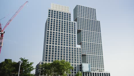 una grúa de construcción se encuentra al lado de un edificio inusual, moderno y de gran altura, que muestra una audaz declaración arquitectónica en greenpoint