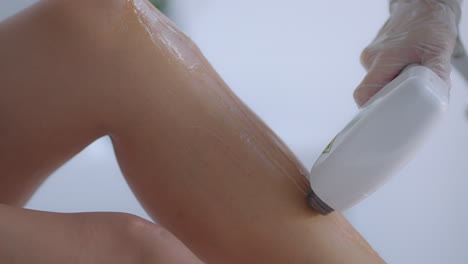 el cosmetólogo hace depilación láser en las piernas del paciente. procedimiento de depilación. procedimiento de depilación con láser de las piernas femeninas. médico con guantes.