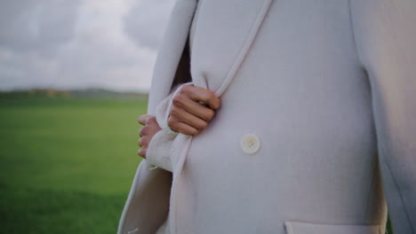 manos tocando abrigo de otoño en clima frío de cerca. mujer elegante ajustar la ropa