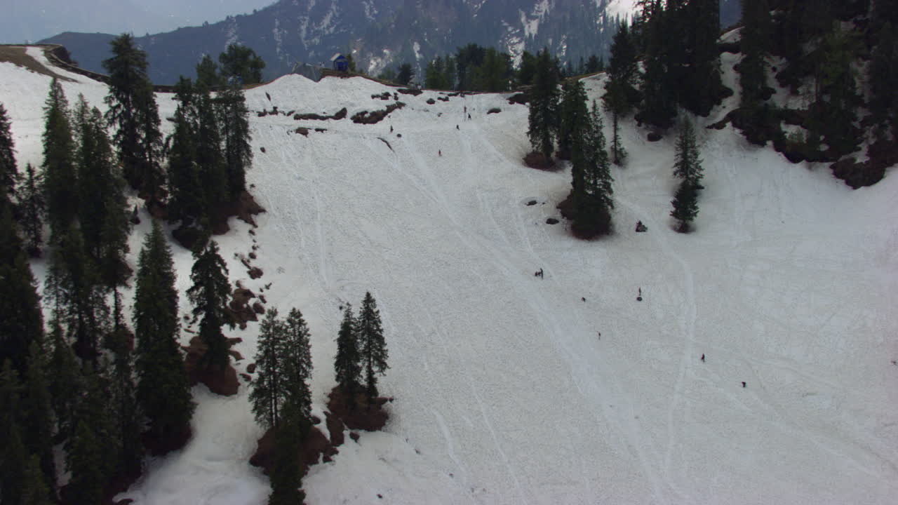 Veduta aerea sulle montagne ghiacciate e la foresta dove le persone sciano e camminano sulle montagne, con un bellissimo sfondo collinare verde e case