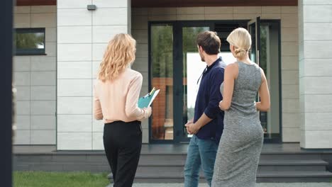 young couple staying near luxury house. group of people talking near new house.