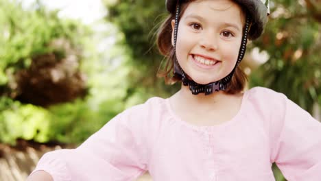 portrait of smiling girl standing with bicycle in park