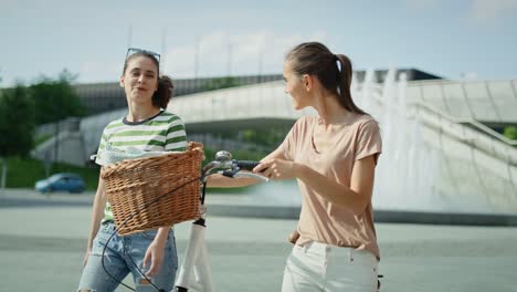 Video-of-two-women-walking-and-talking-with-a-white-bike