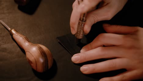 woman hands using a leather swivel knife in the workshop, dark setup, high contrast, color graded