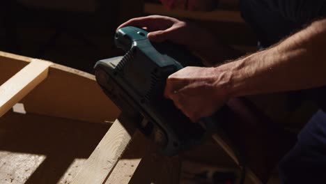 man using a belt sander on wood