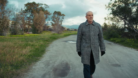 elderly man walking on a dirt road during winter