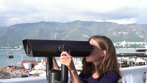 woman looking through binoculars at the beach