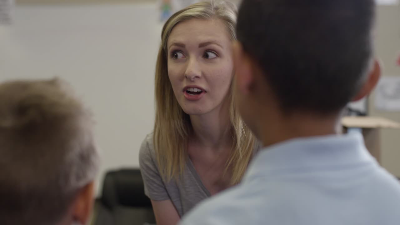 el joven maestro o mentor sonríe y da instrucciones a los estudiantes en el aula