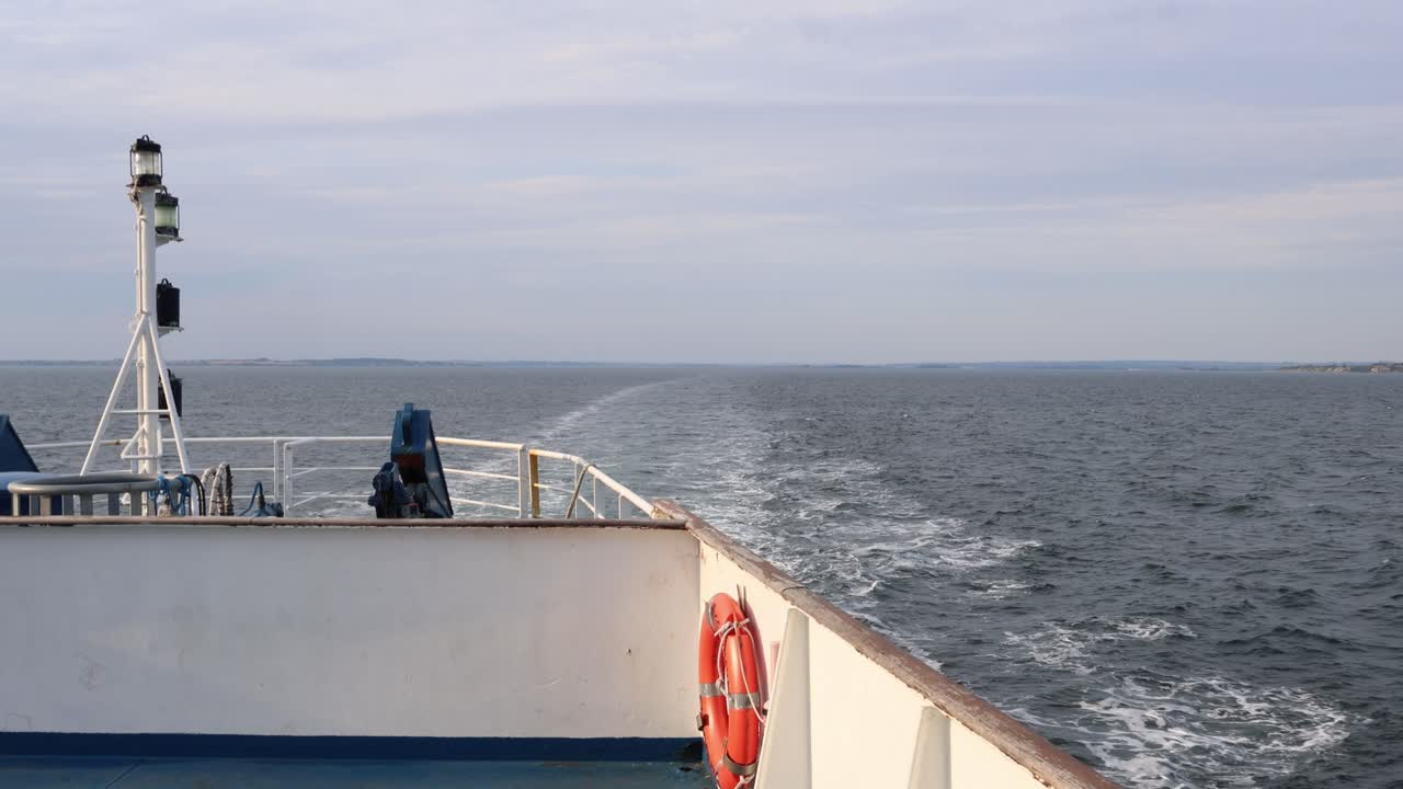 Ein Boot überquert das Wasser und hinterlässt eine Kielspur. Eine Schwimmweste ist auch an Bord